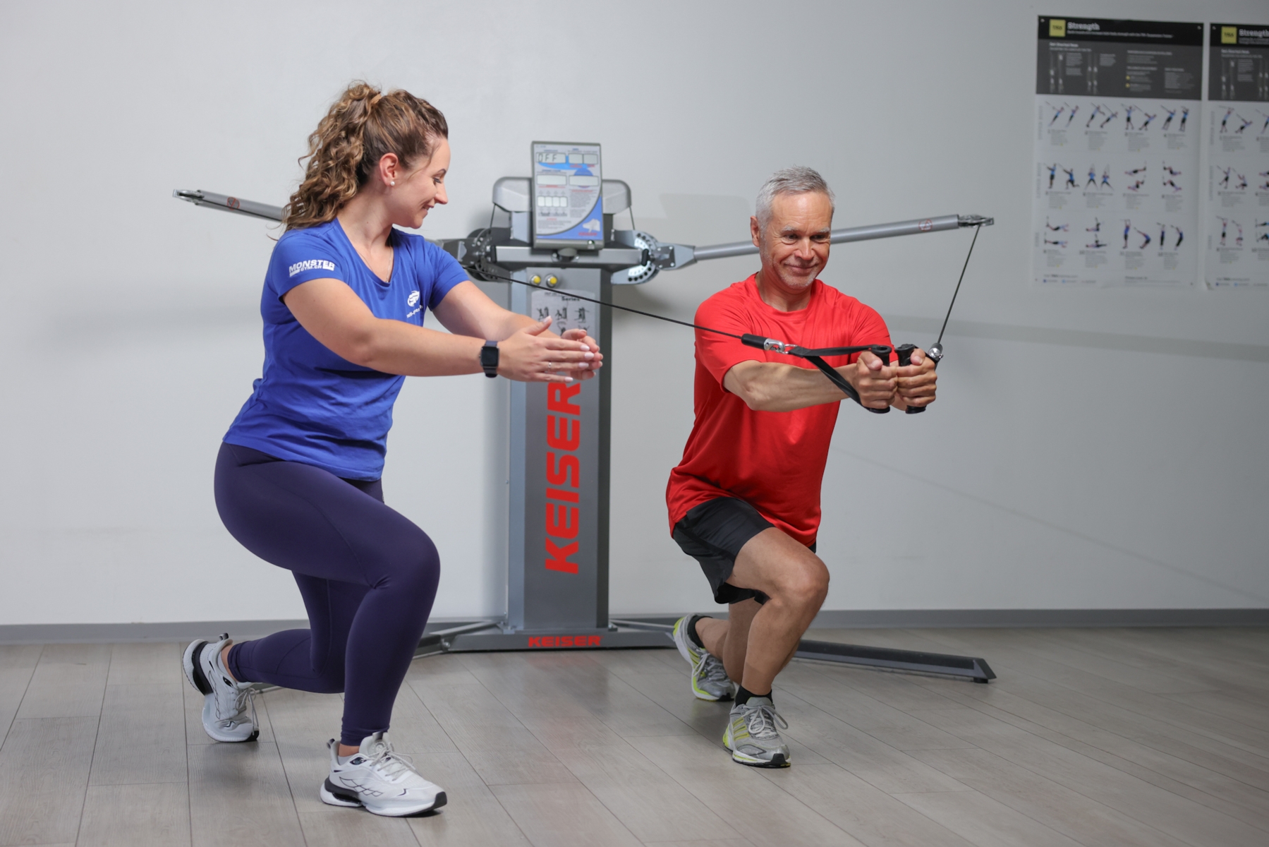 Anleitung eines Kunden bei einer Brustübung am Keiser Functional Trainer.